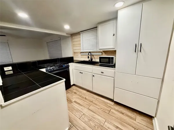 a kitchen with granite countertop white cabinets and black appliances