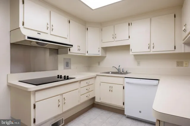 a kitchen with white cabinets and sink