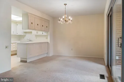 a view of a kitchen with white cabinets and chandelier