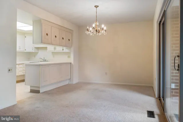 a view of a kitchen with white cabinets and chandelier