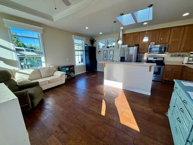 a living room with furniture and kitchen view with wooden floor