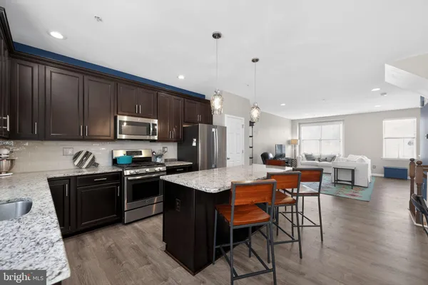 a kitchen with stainless steel appliances granite countertop a table chairs sink refrigerator and cabinets