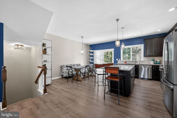 a kitchen with stainless steel appliances kitchen island granite countertop furniture wooden floor and a view of living room
