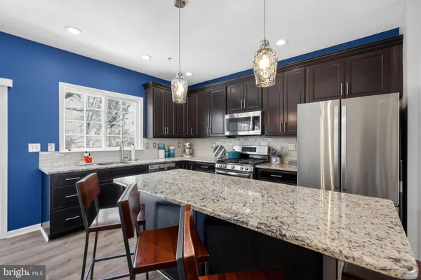 a kitchen with granite countertop a center island and stainless steel appliances