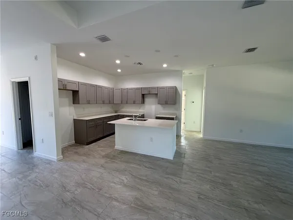 a large kitchen with a large counter top a sink stainless steel appliances and cabinets