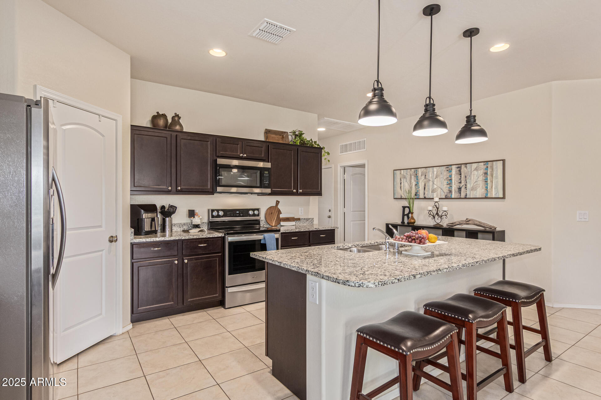 41844 West Rosa Drive Maricopa, AZ 85138 - Photo 21 of 47 a kitchen with kitchen island granite countertop a stove a sink a refrigerator a stove a kitchen island with a dining table and chairs