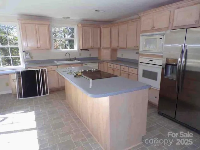 a kitchen with kitchen island granite countertop a stove a sink and a refrigerator