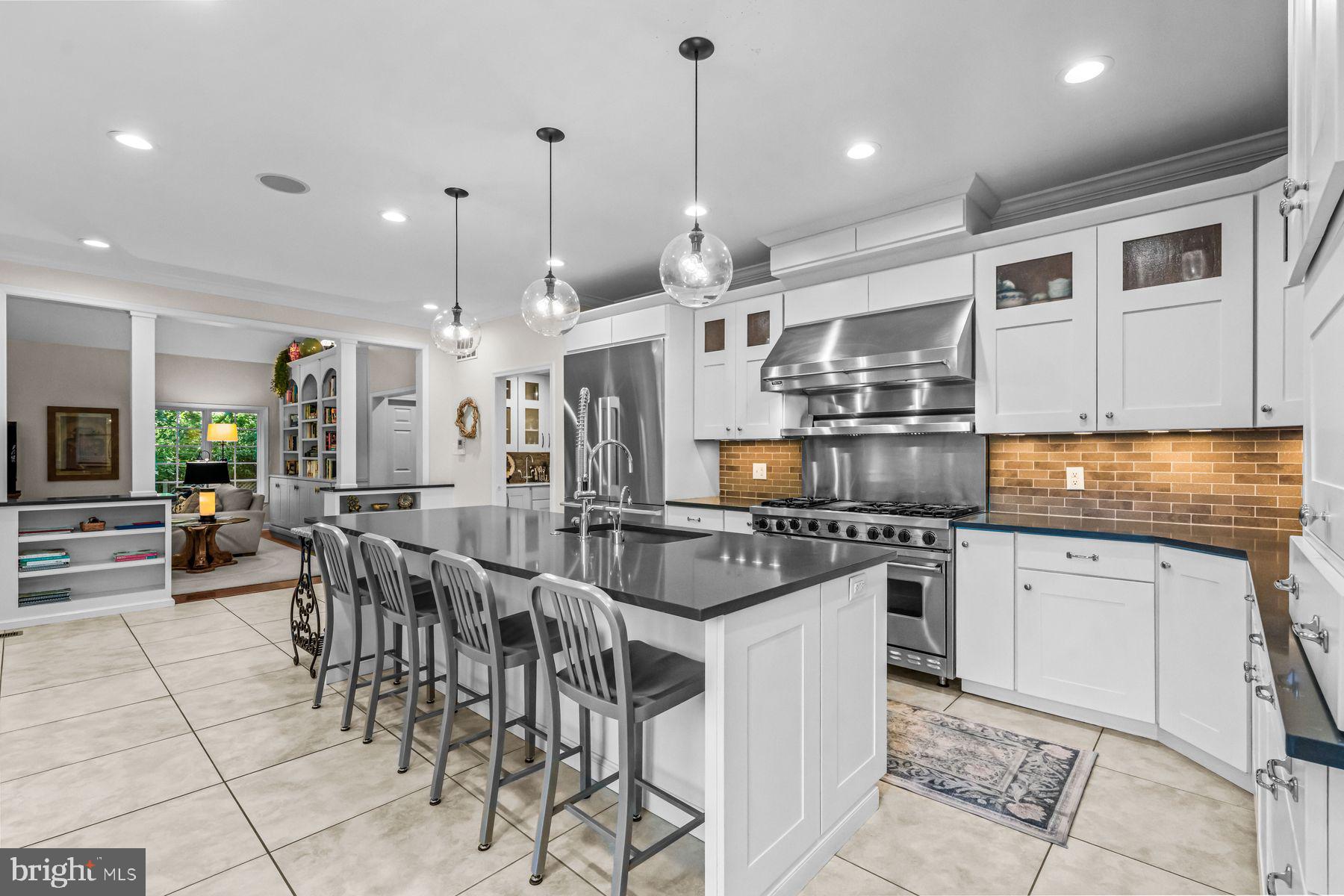 623 Broad Acres Road Penn Valley, PA 19072 - Photo 29 of 78 a kitchen with stainless steel appliances granite countertop a stove top oven a sink a dining table and chairs with white cabinets