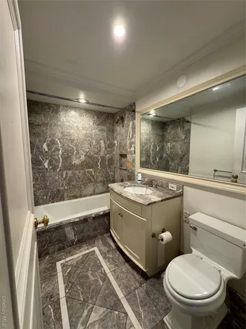 a bathroom with a granite countertop toilet sink and mirror