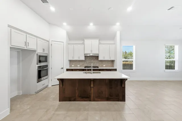 a large kitchen with stainless steel appliances a stove sink and refrigerator