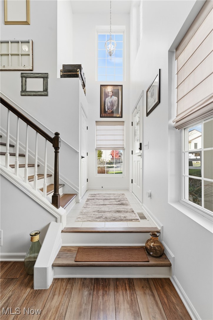 4038 Gardiner Run Akron, OH 44321 - Photo 14 of 38 Stairs featuring wood finished floors, a towering ceiling, and a chandelier