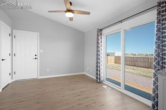 an empty room with sliding glass door and chandelier fan