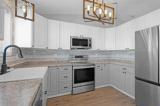 a kitchen with stainless steel appliances granite countertop a stove top oven a sink and white cabinets