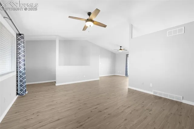an empty room with wooden floor and ceiling fan