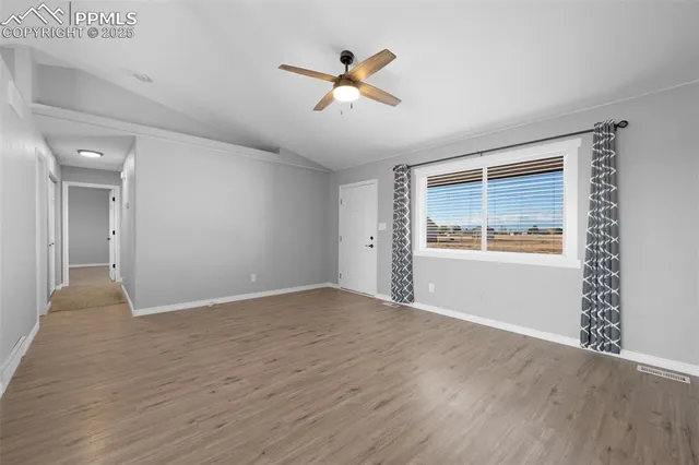 a view of an empty room with window and wooden floor