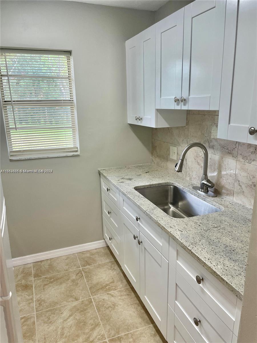 a kitchen with granite countertop white cabinets and sink