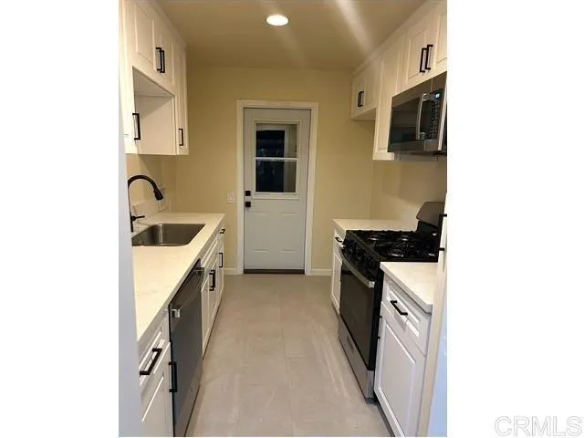 a kitchen with granite countertop a sink a stove top oven a granite counter space and cabinets