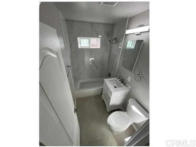 a white toilet sitting next to a bathroom sink and a mirror