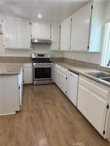 a kitchen with granite countertop a stove a sink and a refrigerator
