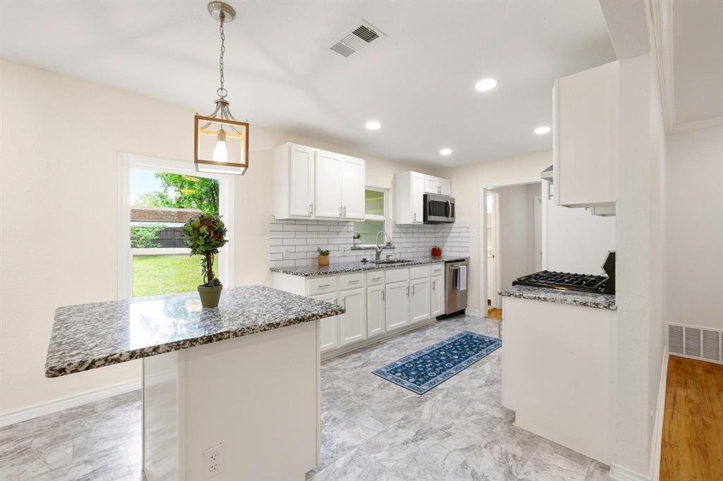 2401 Sunset Street Denison, TX 75020 - Photo 12 of 30 a kitchen with a stove a sink a refrigerator a center island and cabinets