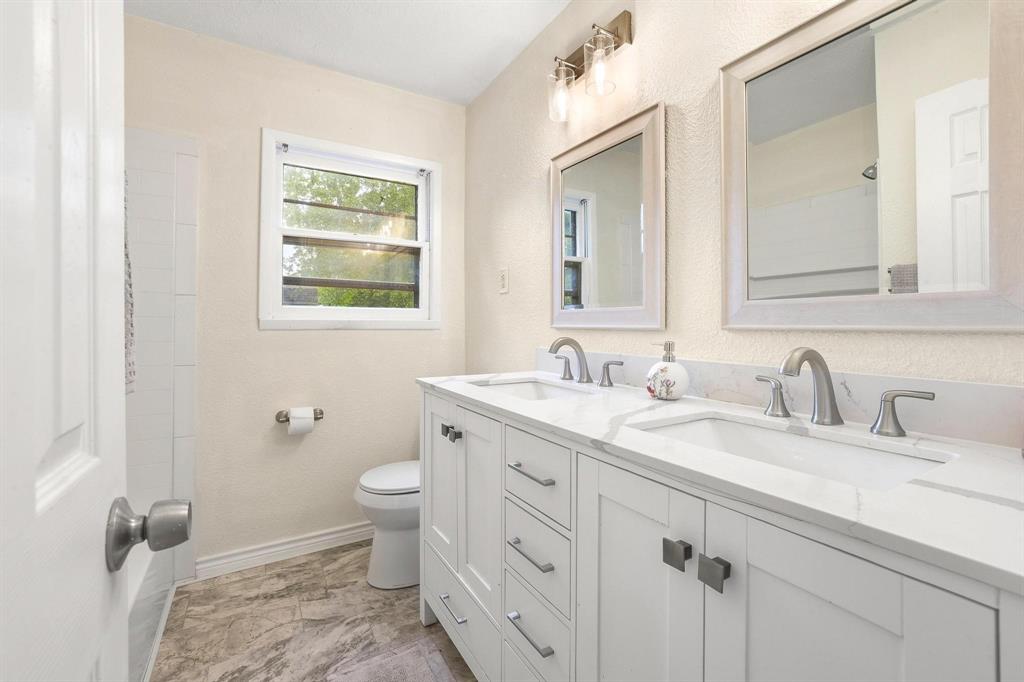 2401 Sunset Street Denison, TX 75020 - Photo 23 of 30 a bathroom with a granite countertop sink toilet and a mirror
