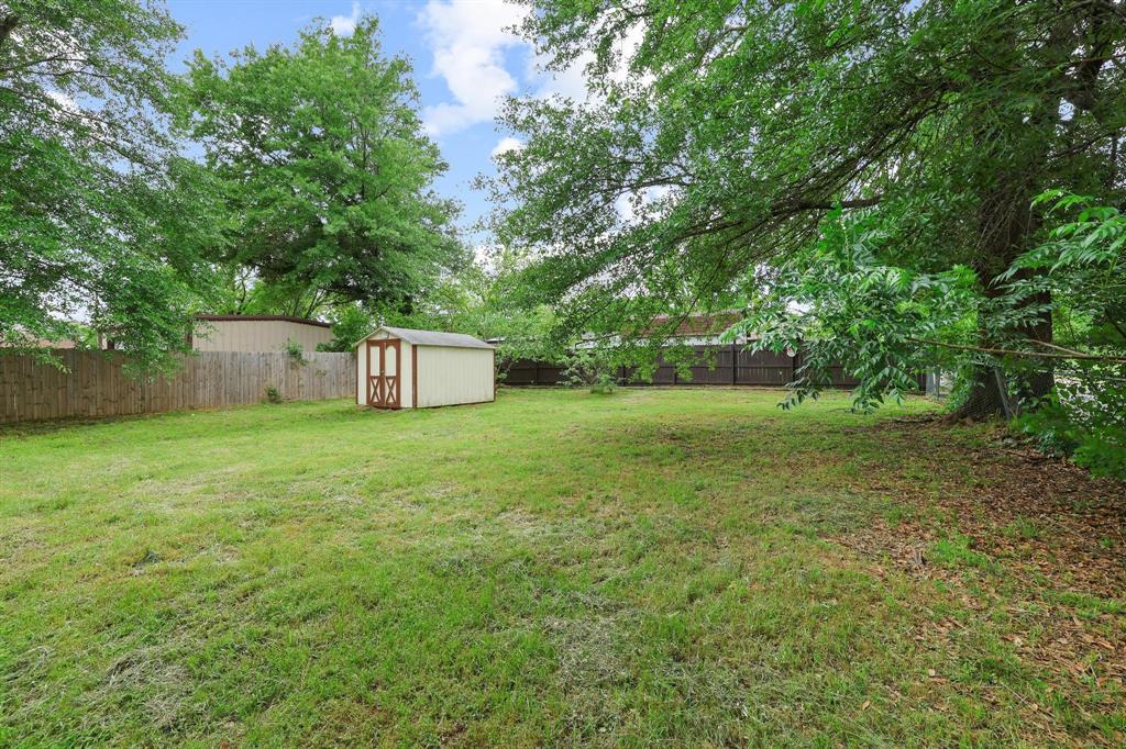 2401 Sunset Street Denison, TX 75020 - Photo 28 of 30 a backyard of a house with large trees and plants