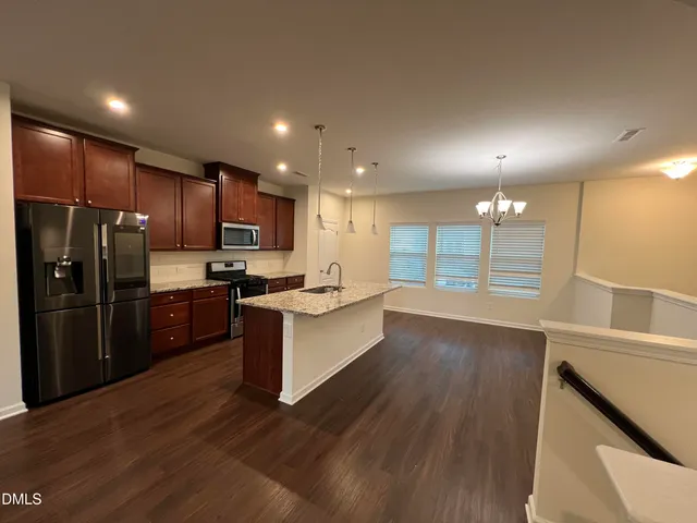a large kitchen with a center island wooden floor stainless steel appliances and cabinets