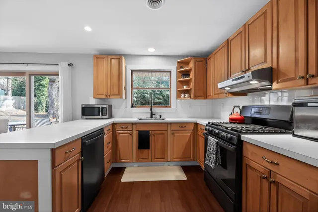 a kitchen with stainless steel appliances granite countertop wooden cabinets a sink dishwasher a stove and a refrigerator with wooden cabinets