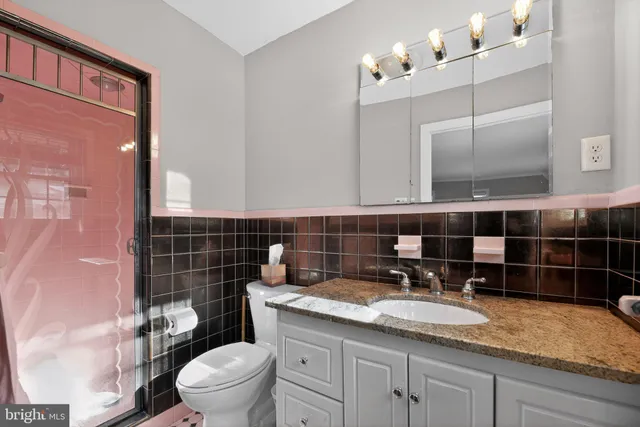 a bathroom with a granite countertop sink a toilet and mirror