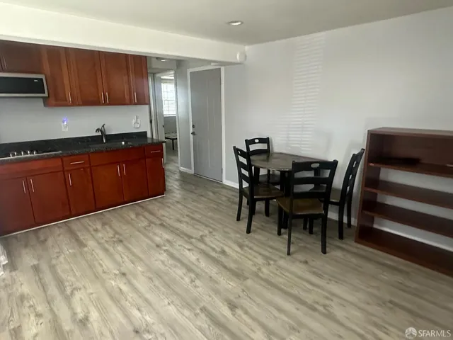 a kitchen with stainless steel appliances kitchen island granite countertop a sink a stove a dining table and chairs with wooden floor