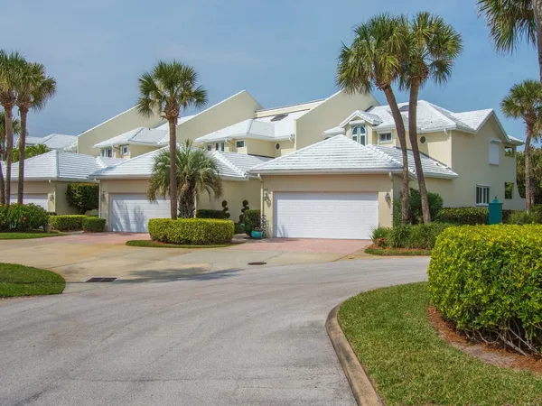 front view of a house with a yard and palm trees