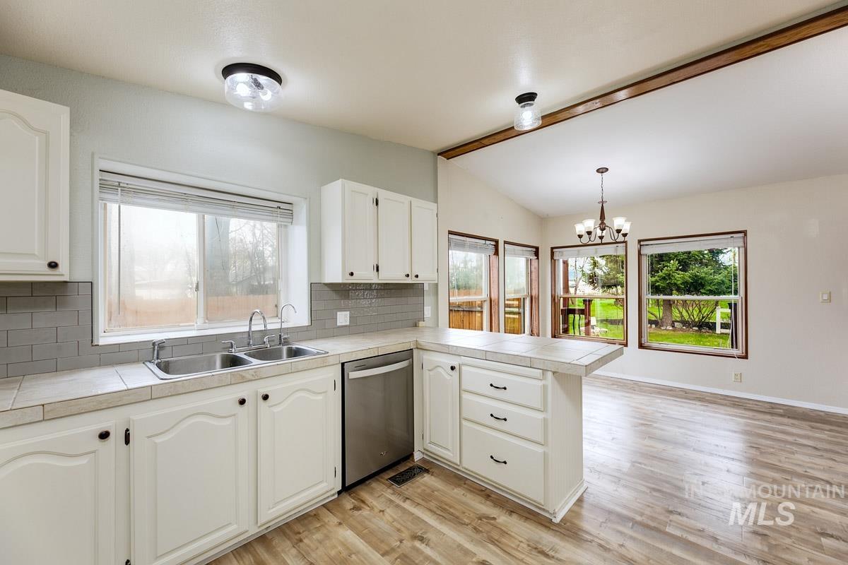 10131 Highway 44 Middleton, ID 83644 - Photo 15 of 42 Kitchen with a chandelier, decorative backsplash, a peninsula, lofted ceiling with beams, and dishwasher