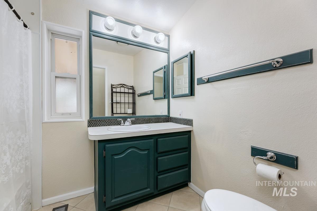 10131 Highway 44 Middleton, ID 83644 - Photo 19 of 42 Full bath featuring vanity, light tile patterned floors, a shower with curtain, and a textured wall