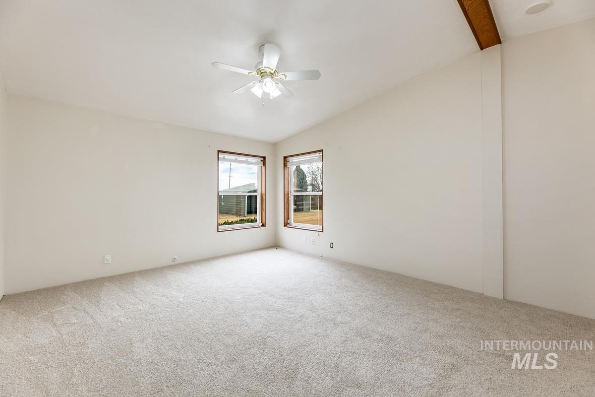 10131 Highway 44 Middleton, ID 83644 - Photo 21 of 42 Spare room with vaulted ceiling with beams, light carpet, and ceiling fan