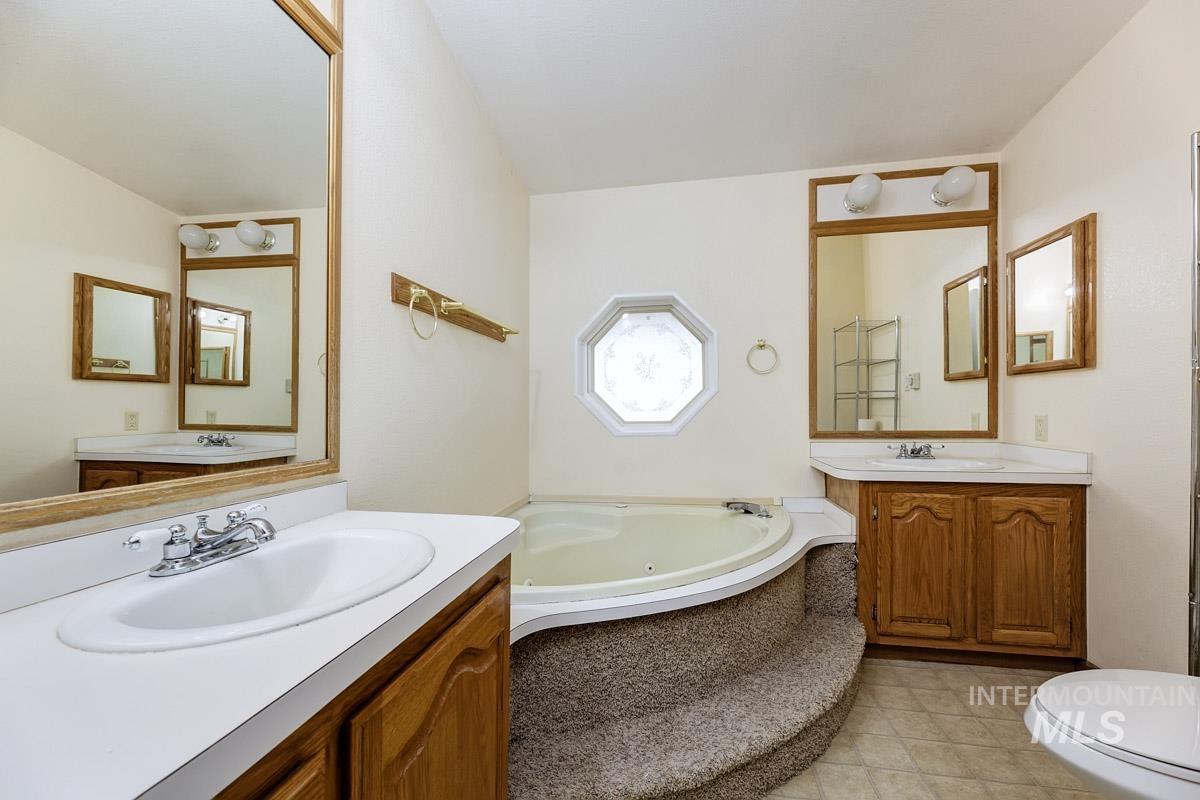 10131 Highway 44 Middleton, ID 83644 - Photo 22 of 42 Full bath with two vanities, a tub with jets, and light tile patterned flooring