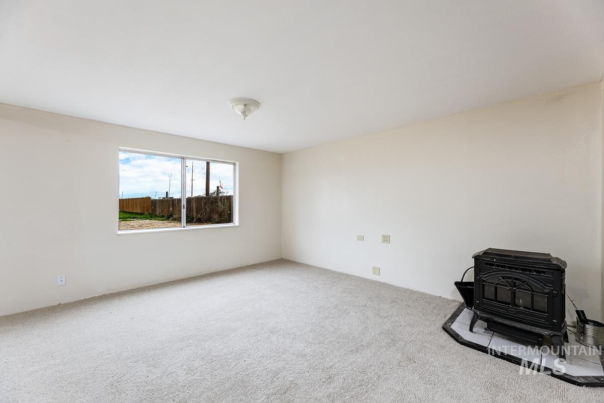 10131 Highway 44 Middleton, ID 83644 - Photo 33 of 42 Carpeted empty room featuring a wood stove