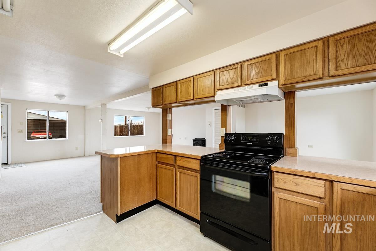 10131 Highway 44 Middleton, ID 83644 - Photo 41 of 42 Kitchen featuring black range with electric cooktop, a peninsula, light countertops, open floor plan, and light colored carpet