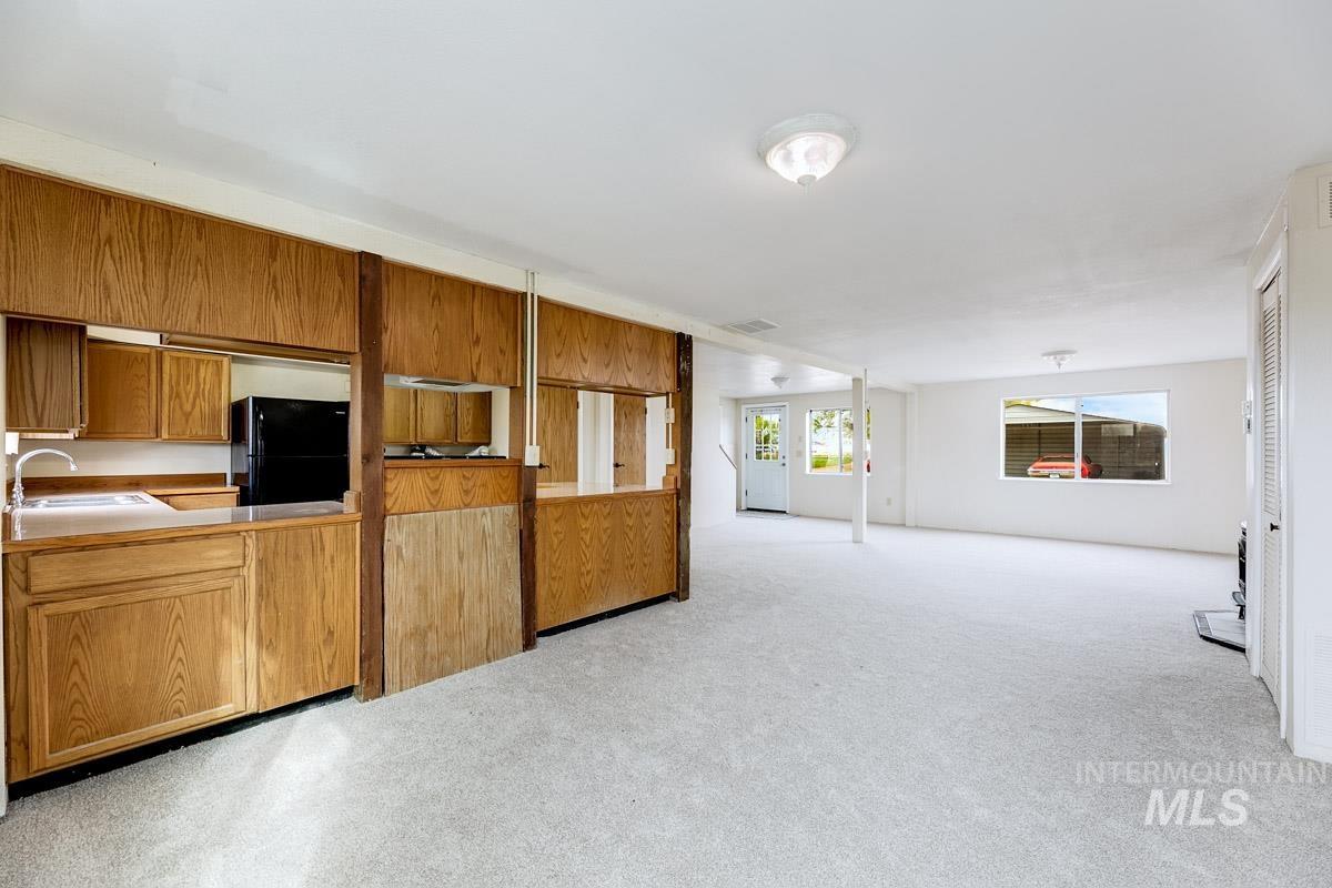 10131 Highway 44 Middleton, ID 83644 - Photo 42 of 42 Kitchen featuring wood finish cabinetry, freestanding refrigerator, light carpet, and open floor plan