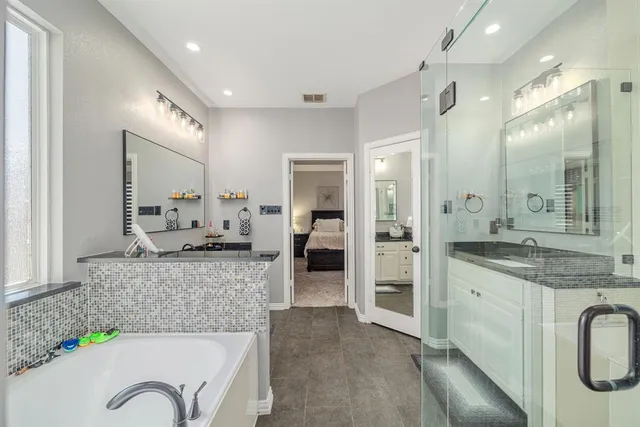 a large bathroom with a granite countertop tub sink and mirror