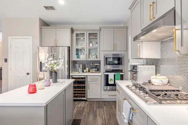 a kitchen with stainless steel appliances kitchen island granite countertop a stove refrigerator and cabinets