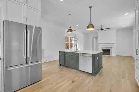 a kitchen with stainless steel appliances granite countertop a refrigerator a sink dishwasher a oven and a wooden floor