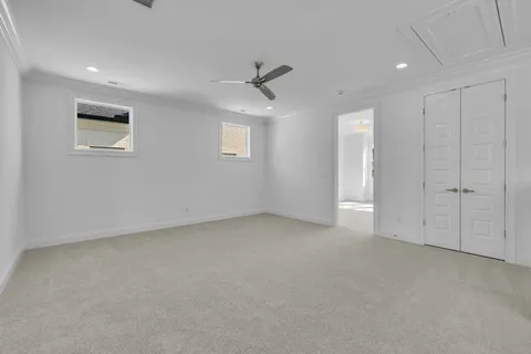 an empty room with a ceiling fan & windows