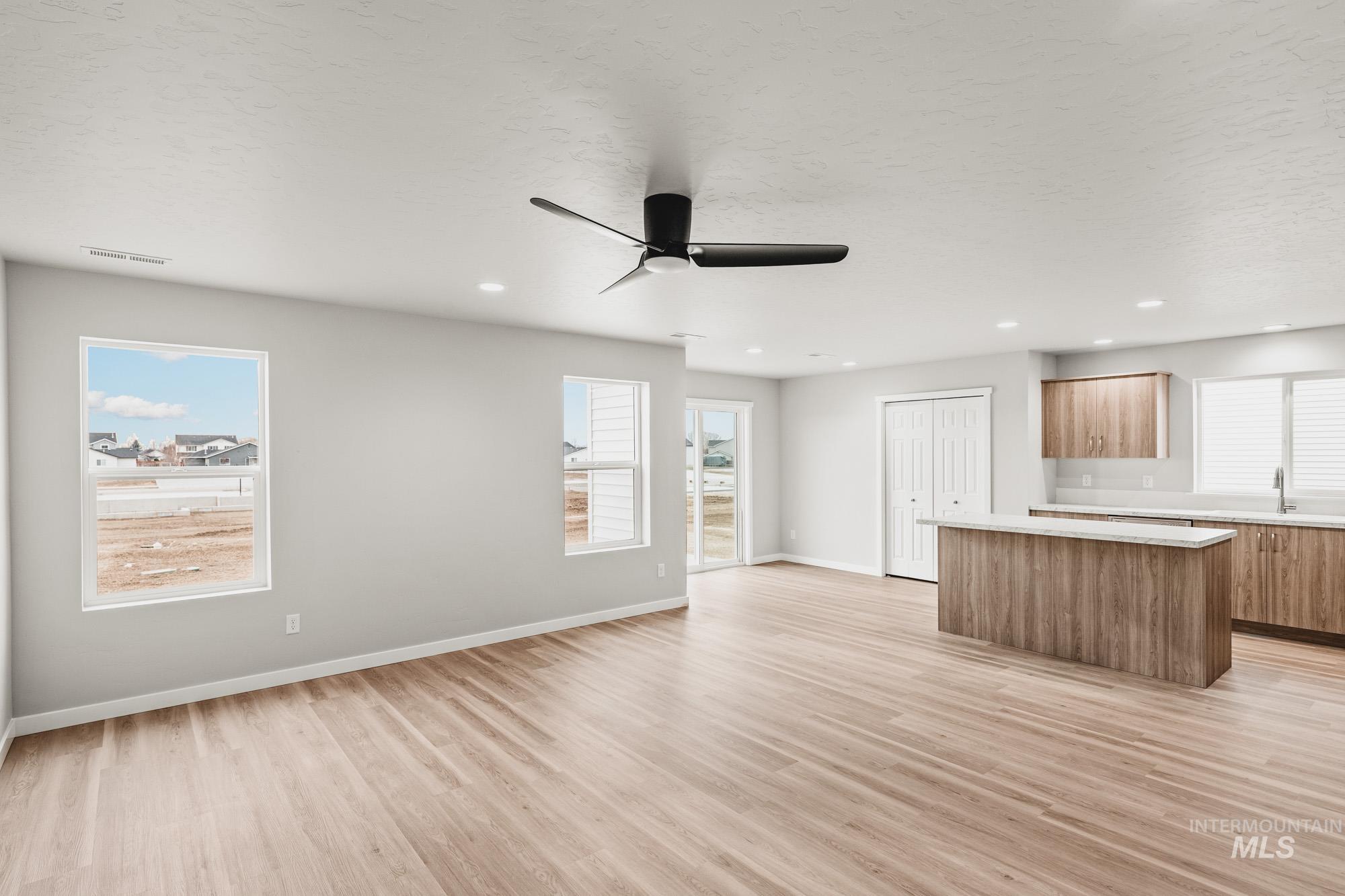 1515 Long Pond Street Middleton, ID 83644 - Photo 9 of 25 Unfurnished living room with a ceiling fan, light wood-style flooring, a textured ceiling, healthy amount of natural light, and recessed lighting