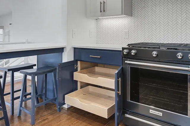 a kitchen with stainless steel appliances granite countertop a sink a stove a dining table and chairs