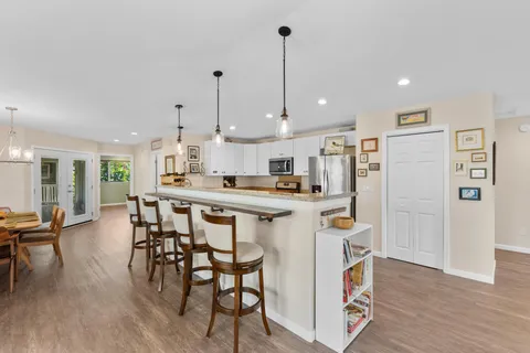 a kitchen with stainless steel appliances kitchen island wooden floors and white cabinets