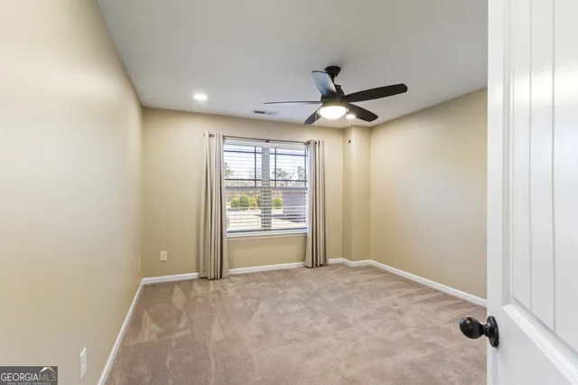 a view of an empty room with a window and a kitchen
