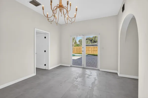 a view of an empty room with window and kitchen view