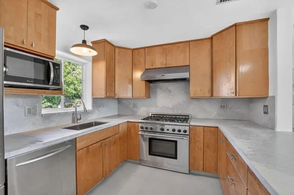a kitchen with stainless steel appliances granite countertop a sink a stove and a microwave