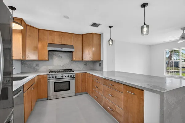 a kitchen with stainless steel appliances granite countertop a stove a sink and white cabinets