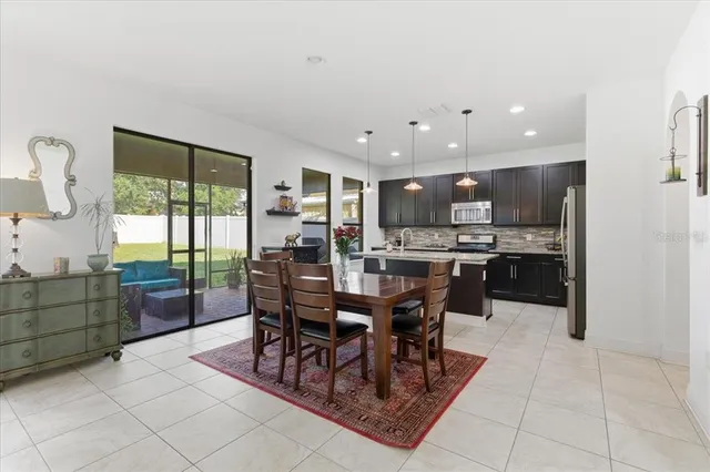 a kitchen with stainless steel appliances kitchen island granite countertop a table chairs and a refrigerator